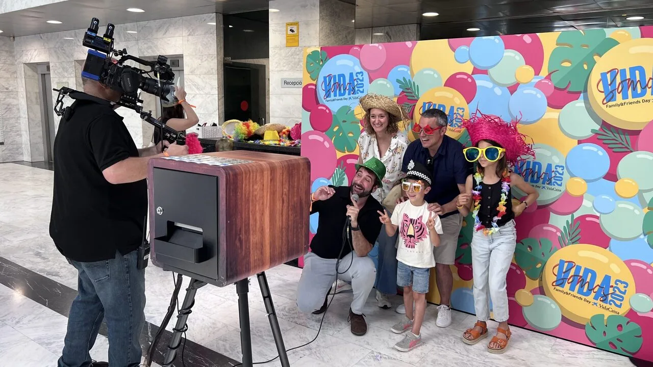 Grupo de personas disfrutando de un fotomatón con accesorios divertidos en un evento.