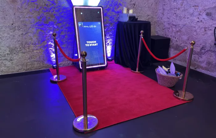 Fotomatón espejo con alfombra roja y postes con cordón en un evento