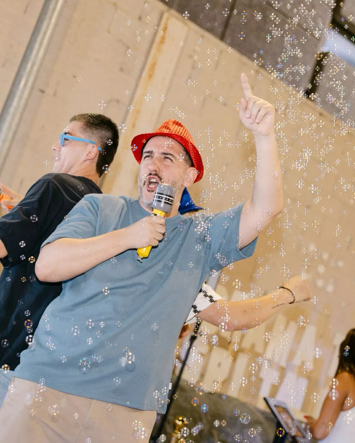 Invitado con sombrero rojo y micrófono entre burbujas en el evento de Obramat con el Fotomatón 360