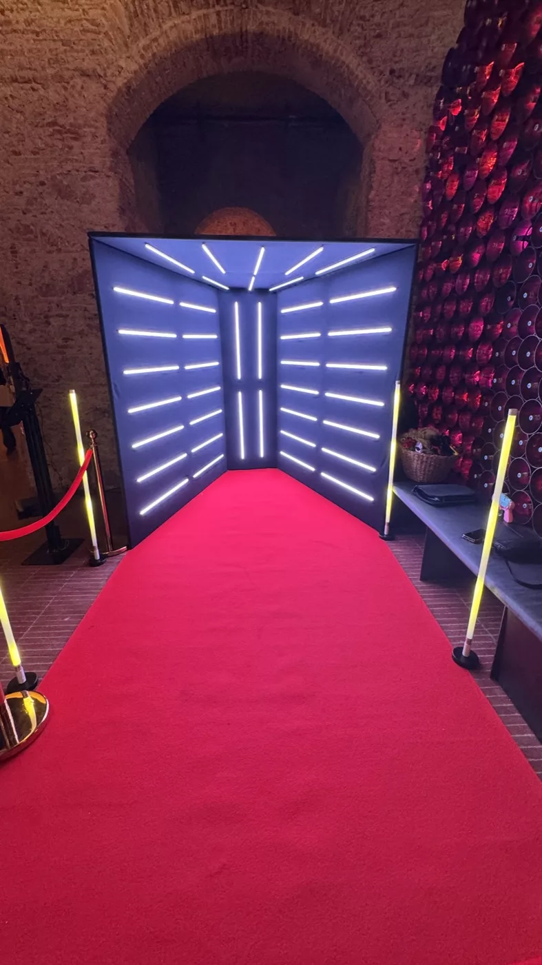 Glam Video Booth light tunnel with a red carpet and gold rope barriers